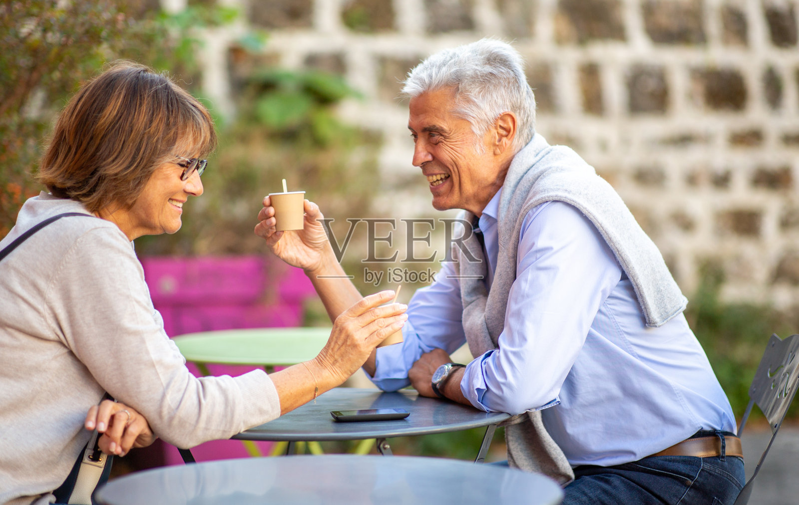 一对老夫妇在外面的桌子上喝咖啡，面带微笑照片摄影图片