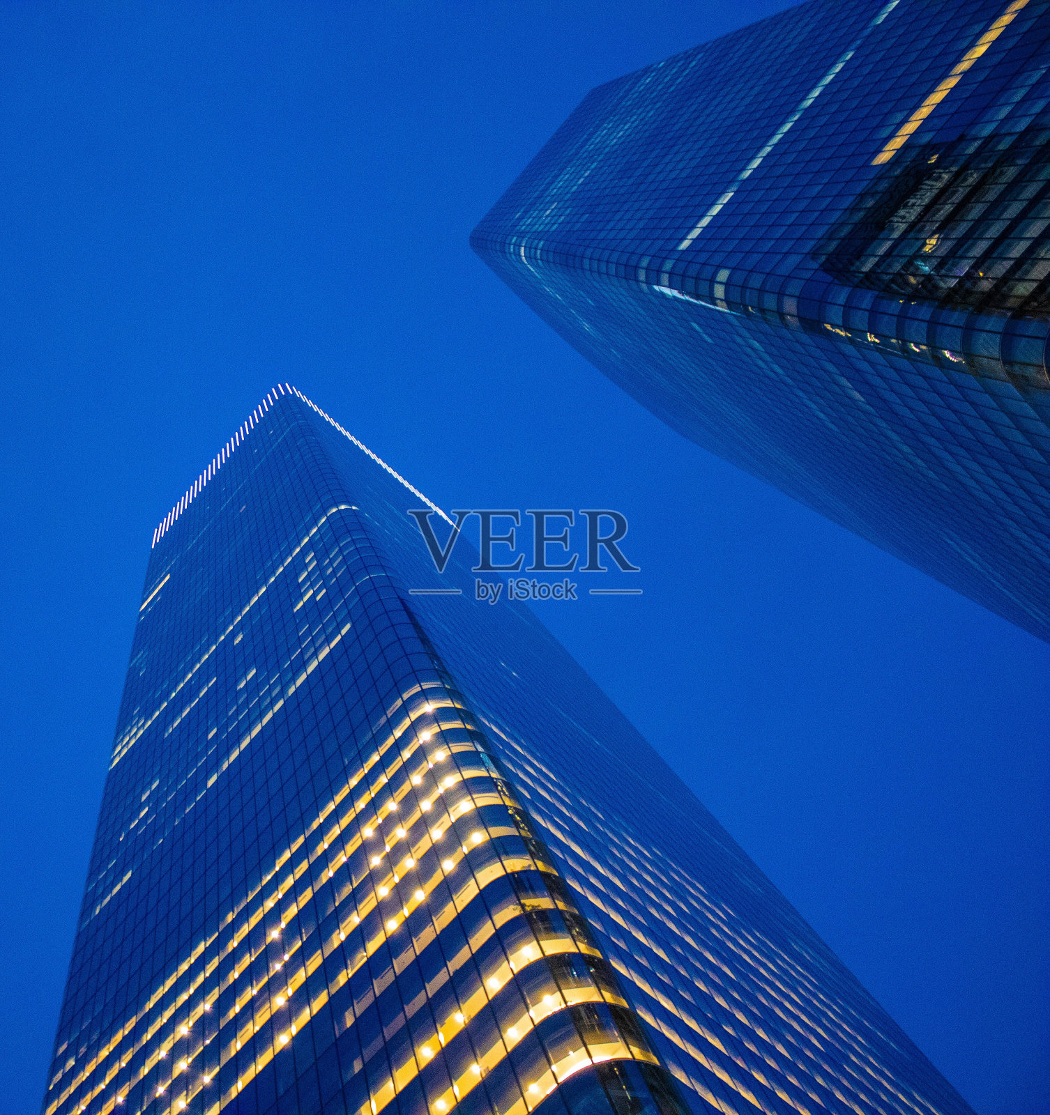 两座摩天大楼在夜晚被下面的灯光照亮照片摄影图片