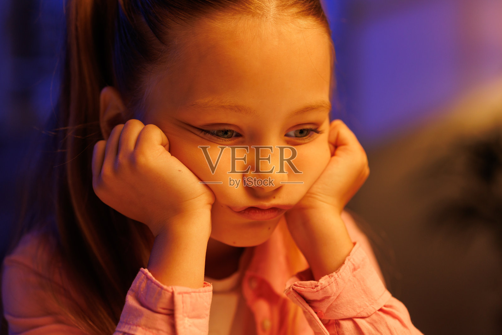 晚上，小女孩伤心地坐在客厅的桌旁，厌倦学习，情绪低落照片摄影图片