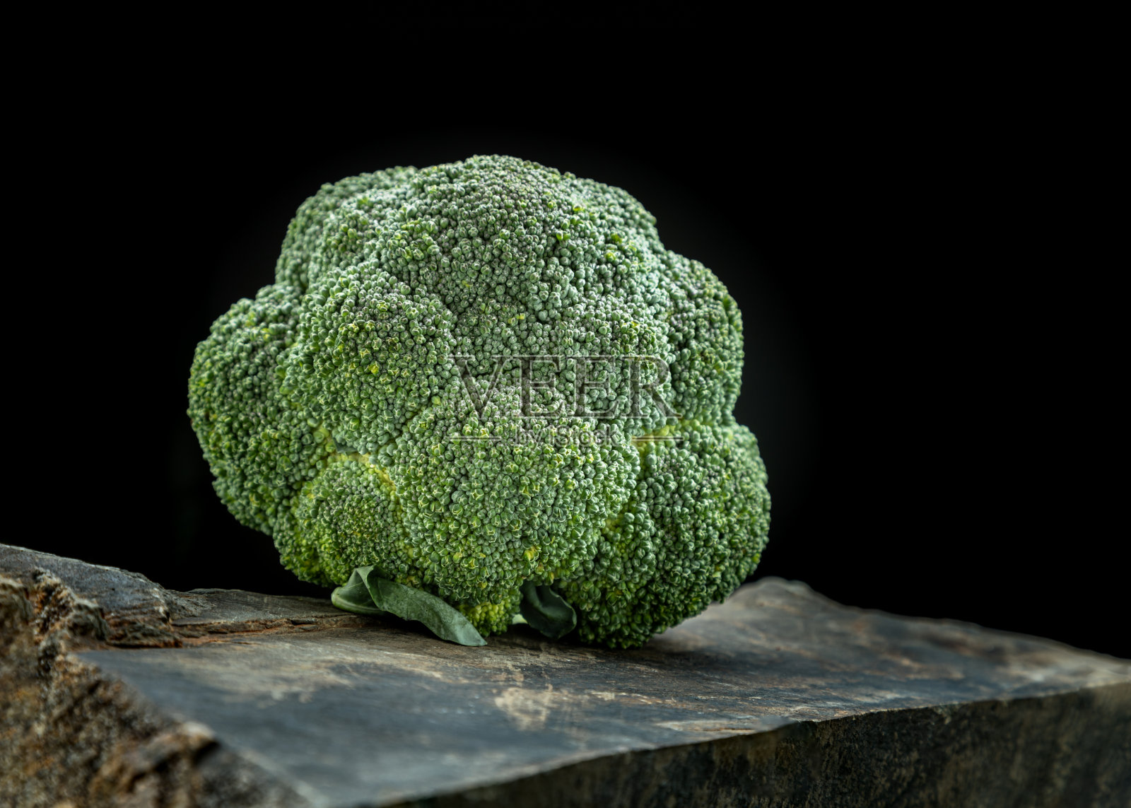 新鲜的绿色西兰花在黑色的岩石与黑暗的背景。照片摄影图片