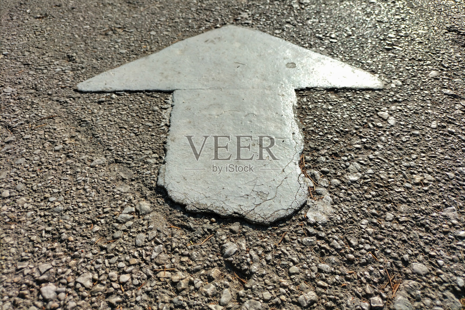 在人行道上指示、控制行人移动方向的箭头，用白色油漆制成，在柏油路上有轻微模糊的边缘。控制人口流动的概念照片摄影图片