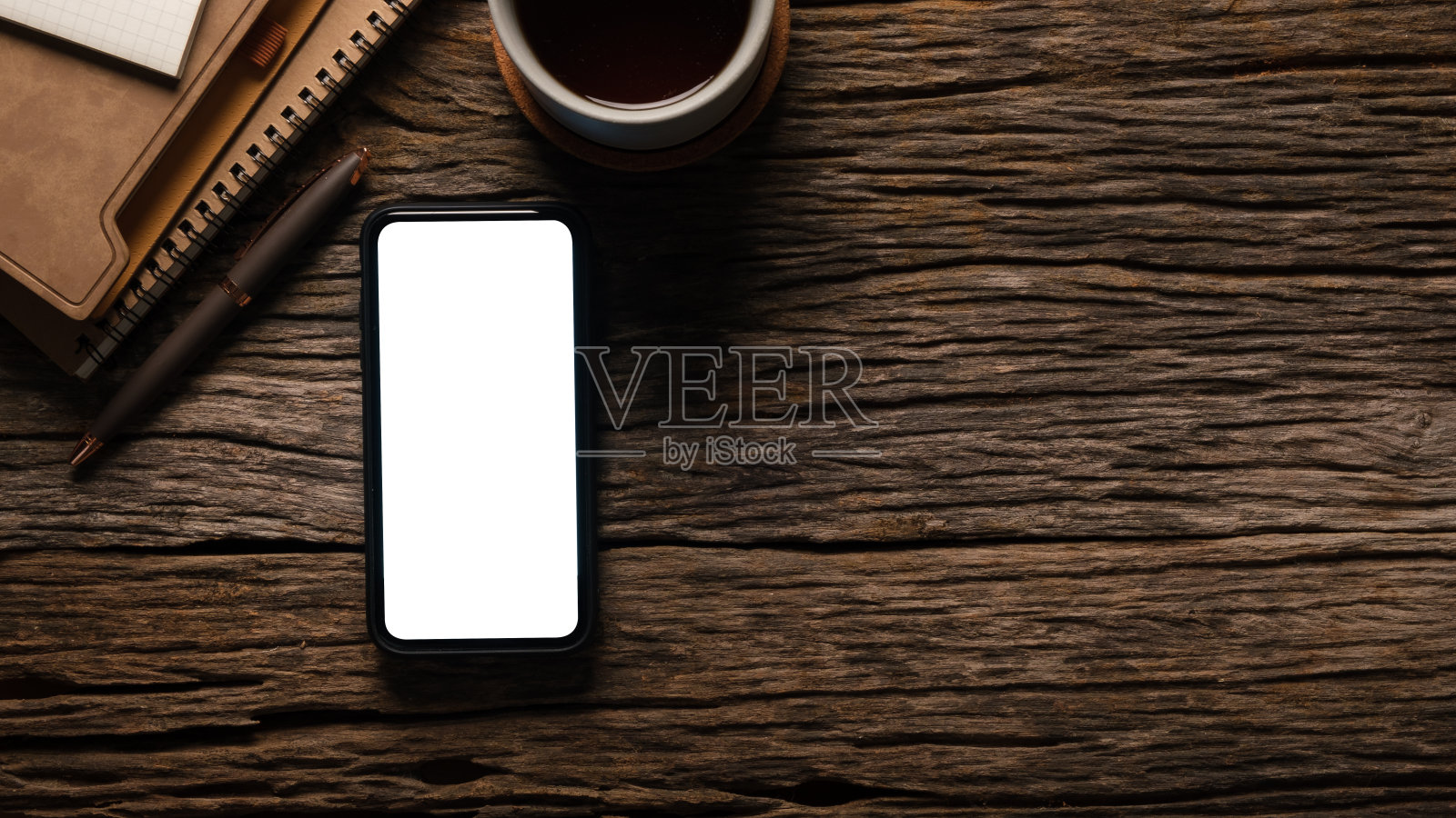 现代工作场所，木桌上有智能手机笔记本。为您的广告设计复制空间和空白屏幕。照片摄影图片