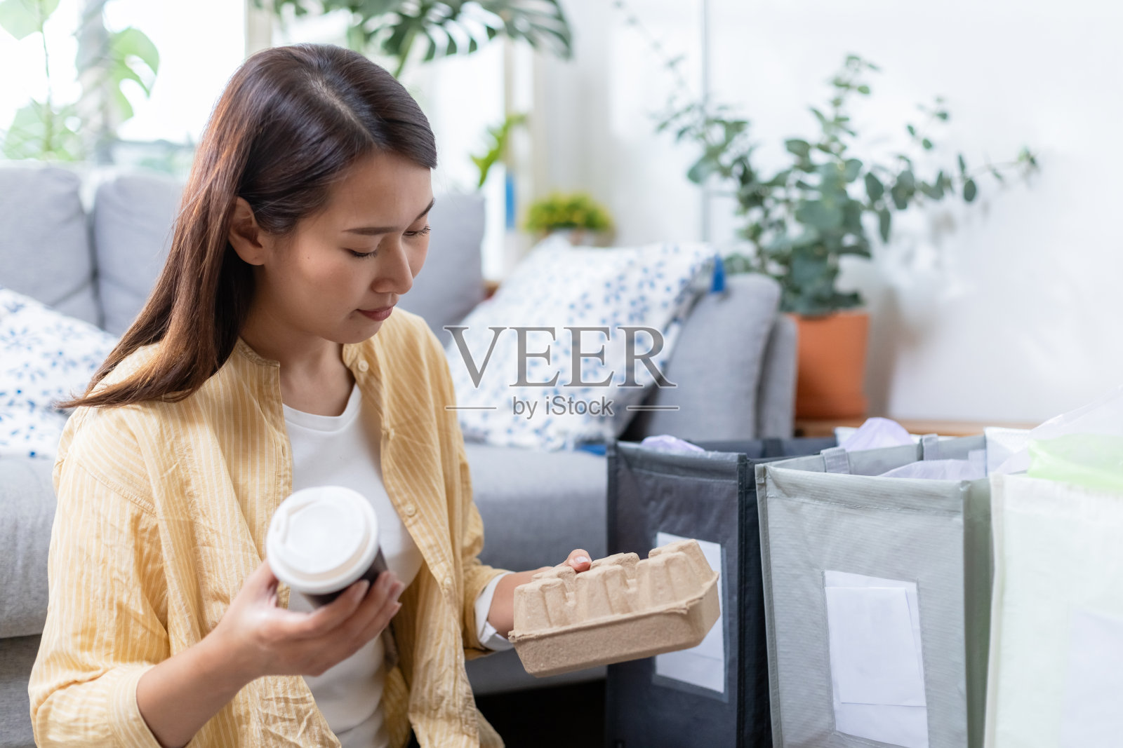 亚洲年轻女性坐在家里分拣废纸和塑料垃圾。垃圾分类回收。减少全球变暖。环保理念。照片摄影图片