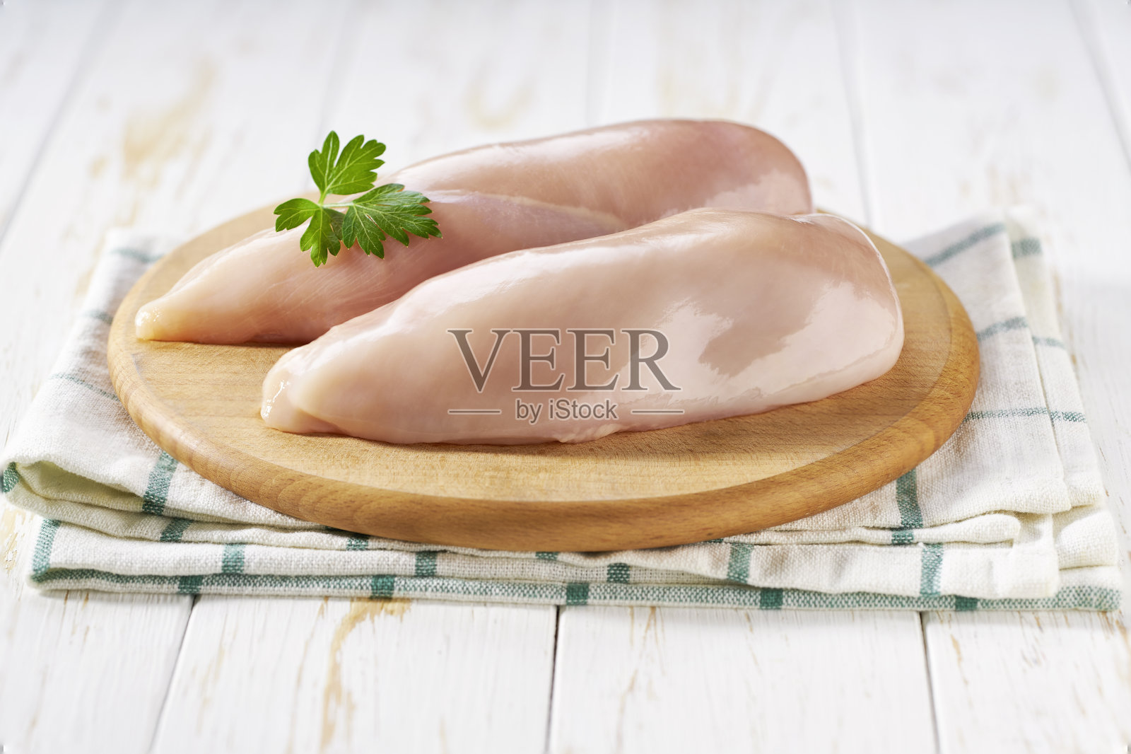 生的去皮鸡胸片和欧芹放在砧板上，复制文字空间。照片摄影图片