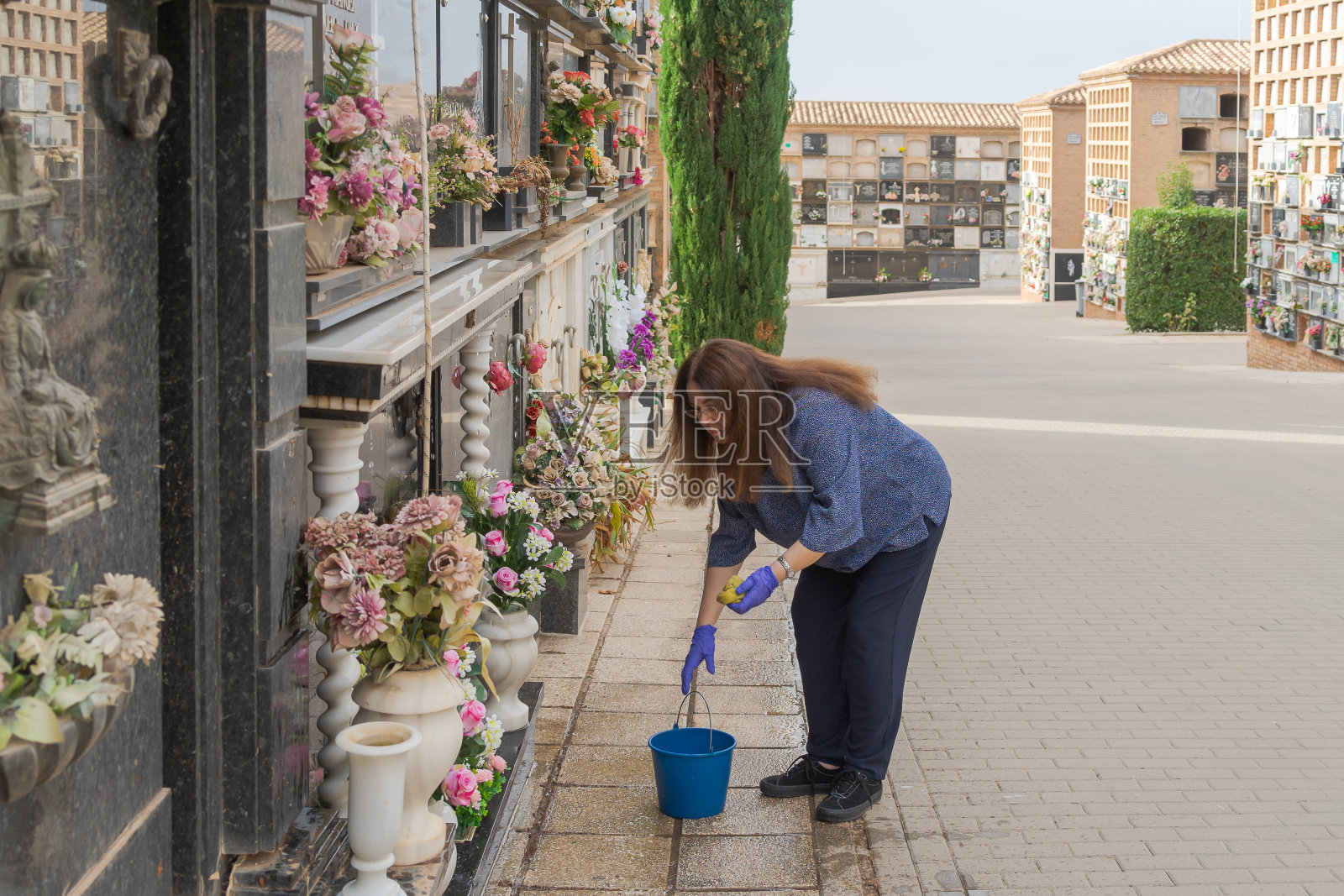 女人在万圣节清扫家人的坟墓照片摄影图片