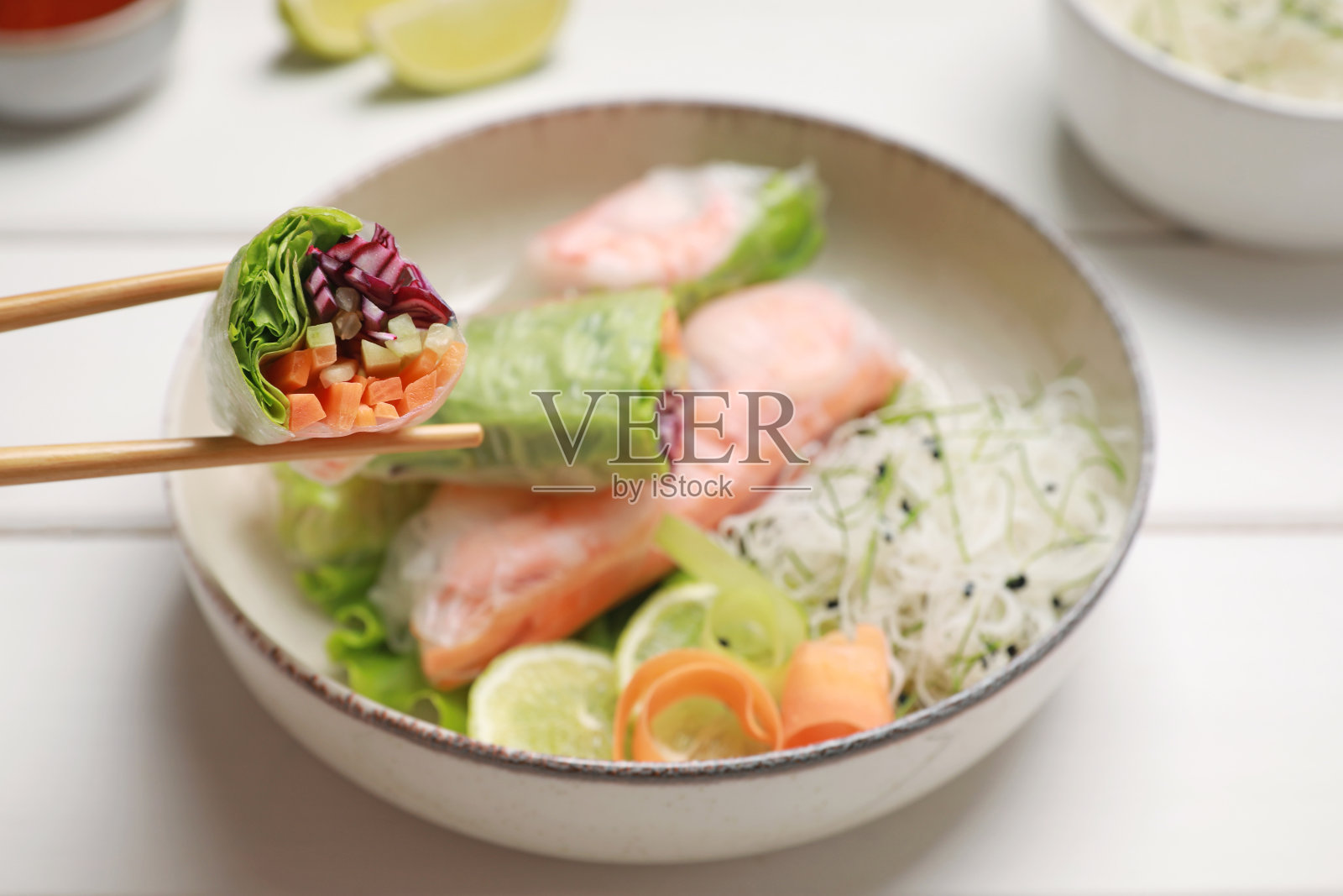 白色木桌上裹着宣纸的美味春卷，特写照片摄影图片