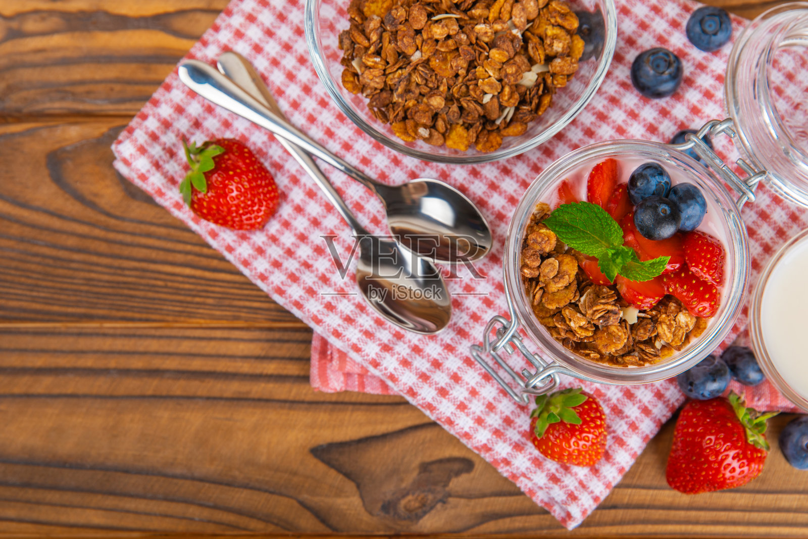 一碗格兰诺拉麦片，酸奶和新鲜浆果放在质地桌上。酸奶浆果，巴西莓碗，螺旋藻碗。健康食物，均衡早餐。草莓，蓝莓，猕猴桃，桃子，杏仁和奇亚。照片摄影图片