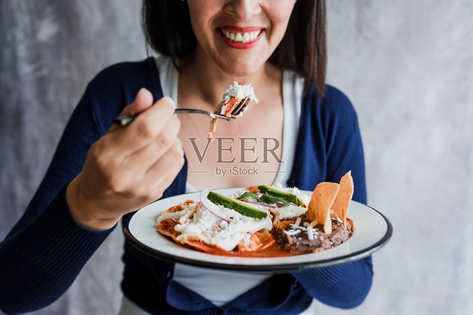 墨西哥妇女吃着红酱辣椒，在墨西哥拉丁美洲，西班牙人的早餐中烹饪传统的墨西哥食物照片摄影图片