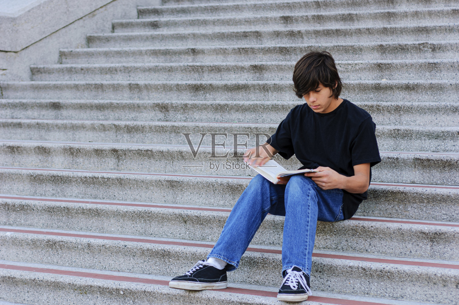 在学校台阶上学习的拉丁裔少年照片摄影图片