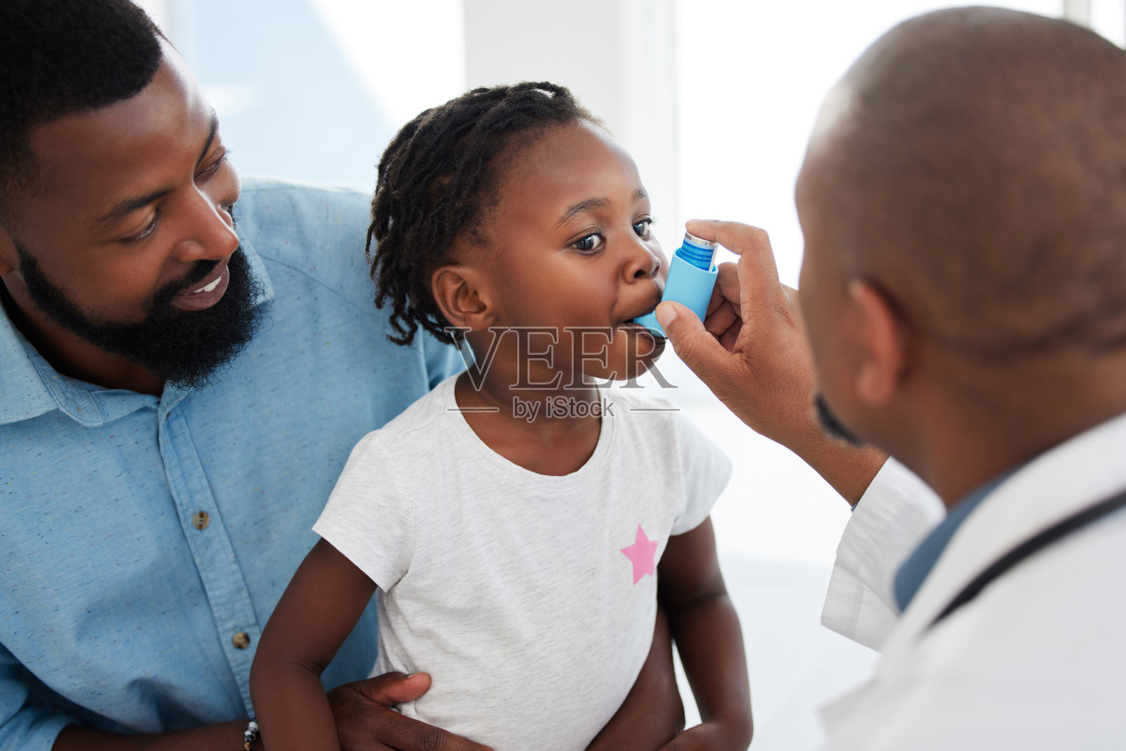 医生在诊所的办公室里帮助一个患有哮喘吸入器的儿童病人。在儿童医院，医护人员用泵给患有胸部或呼吸系统疾病的女孩咨询照片摄影图片