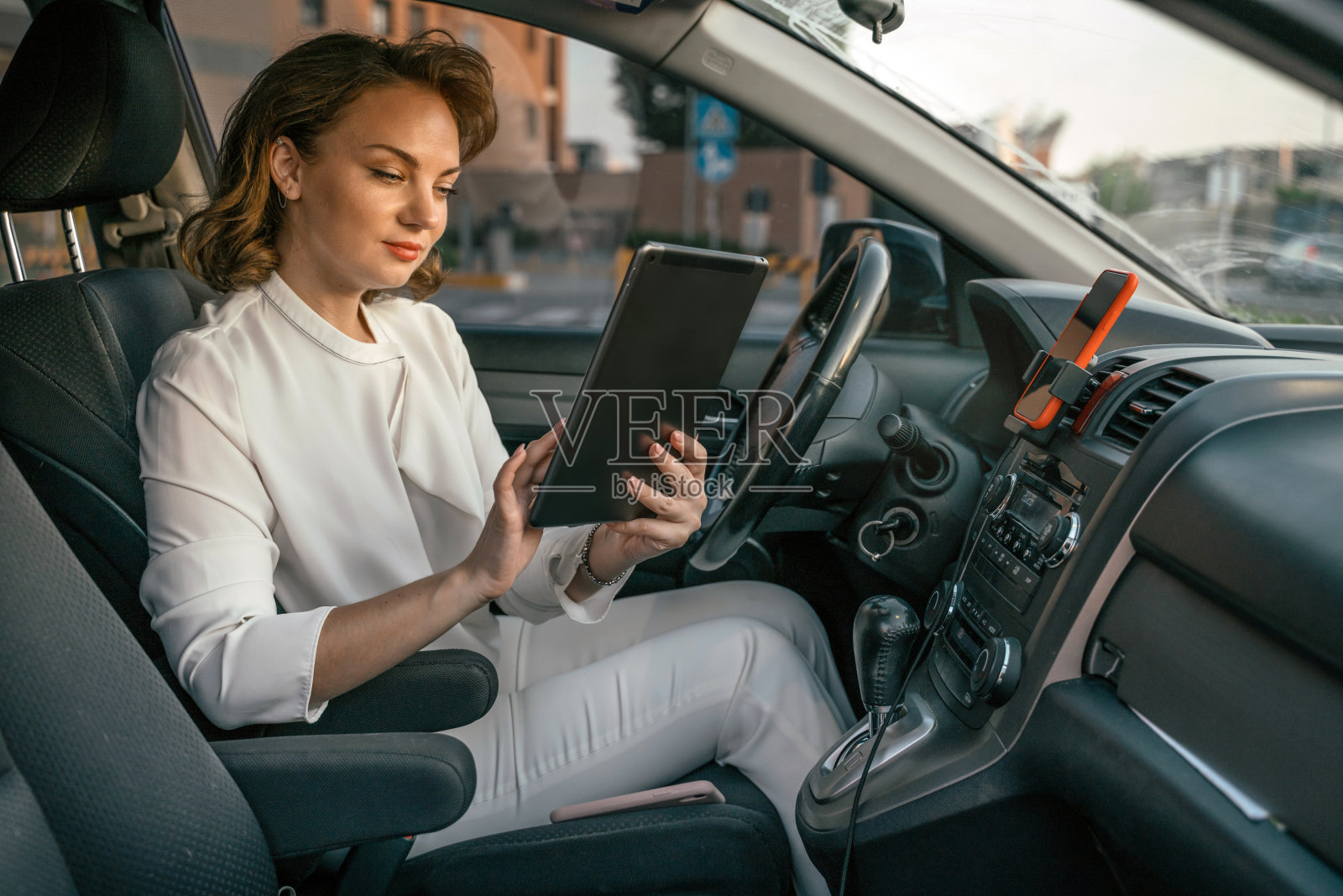 司机使用数码平板电脑在线工作，坐在新的舒适的车。运输的概念照片摄影图片