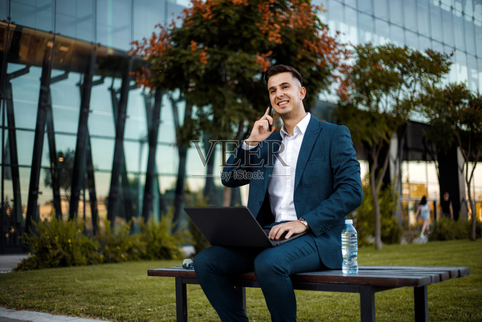 经理正坐在公司前面的长凳上讲电话照片摄影图片