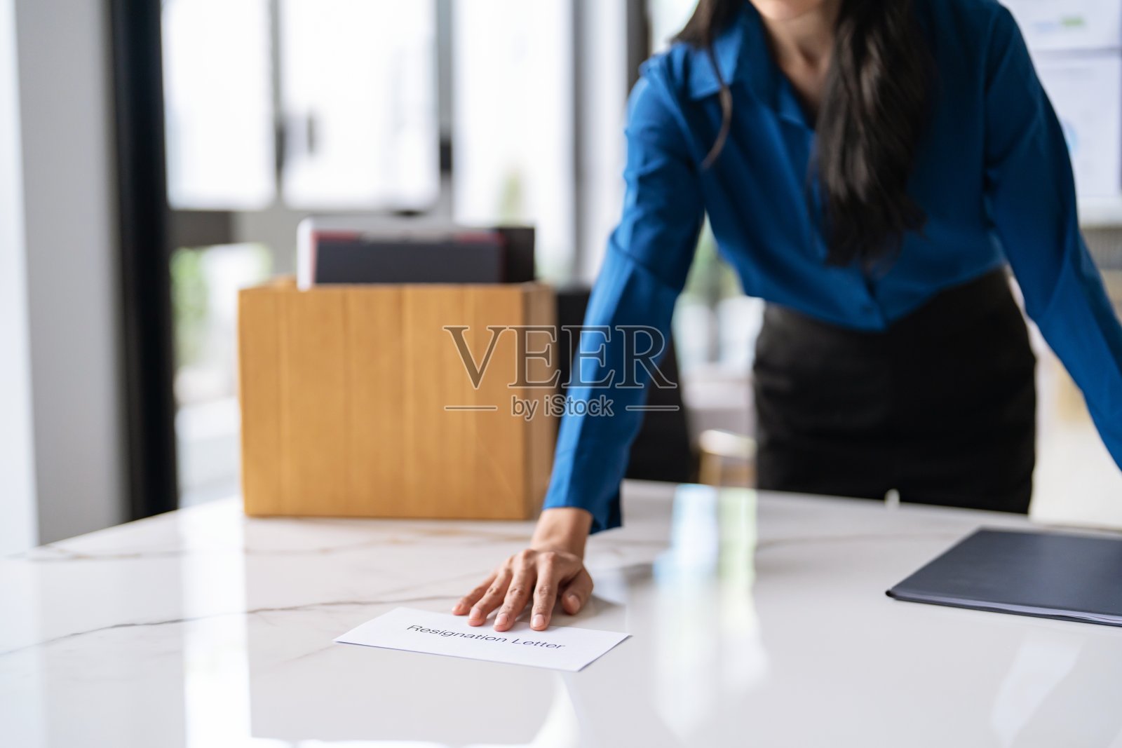 职场女性发送辞职信和打包物品辞职抑郁症或在办公室的办公桌上拎着商务纸板箱。换工作或被公司解雇照片摄影图片