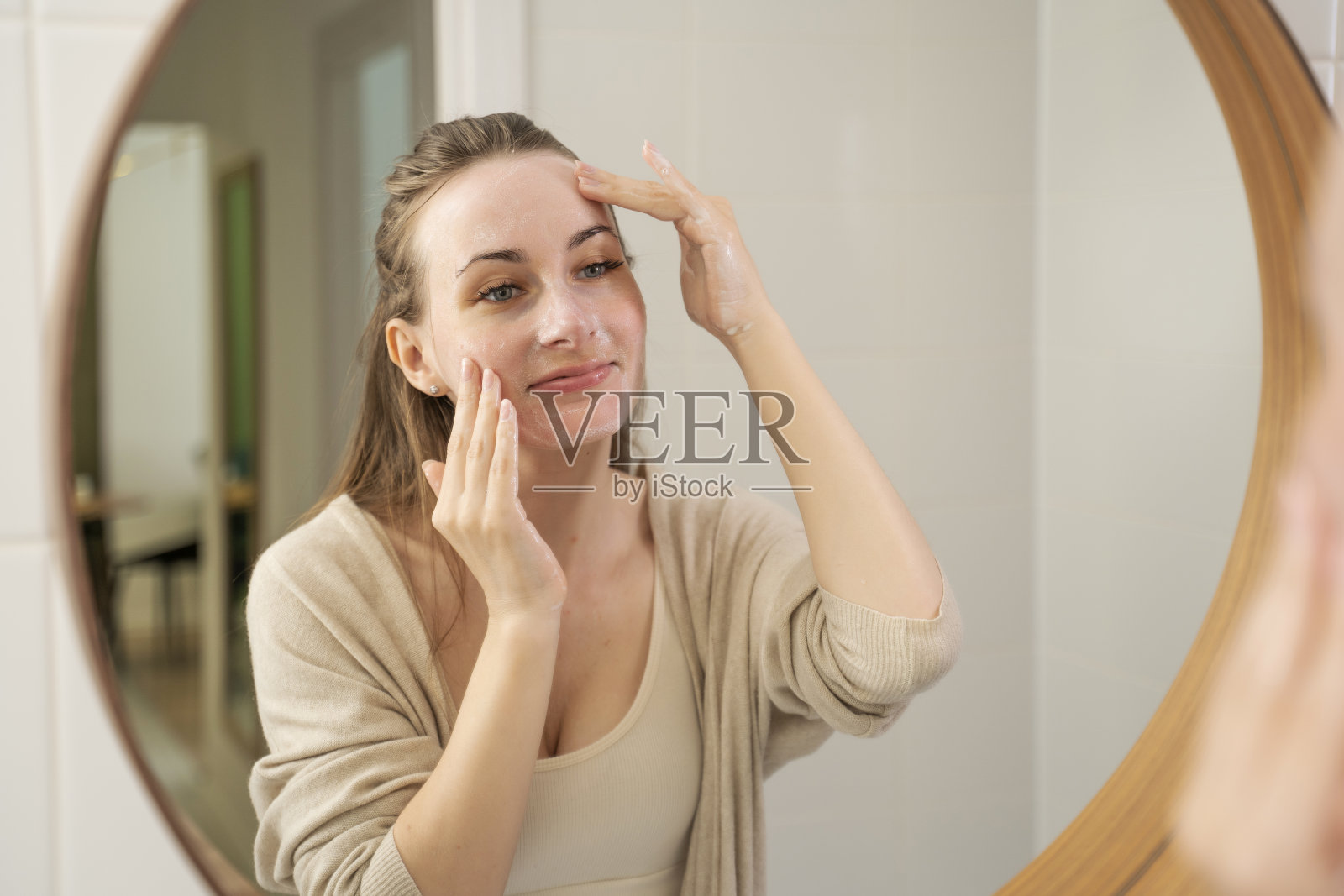 开朗的笑着的女人在涂洗面奶。一个可爱的黑发女郎，外表迷人。水疗放松护肤的概念照片摄影图片