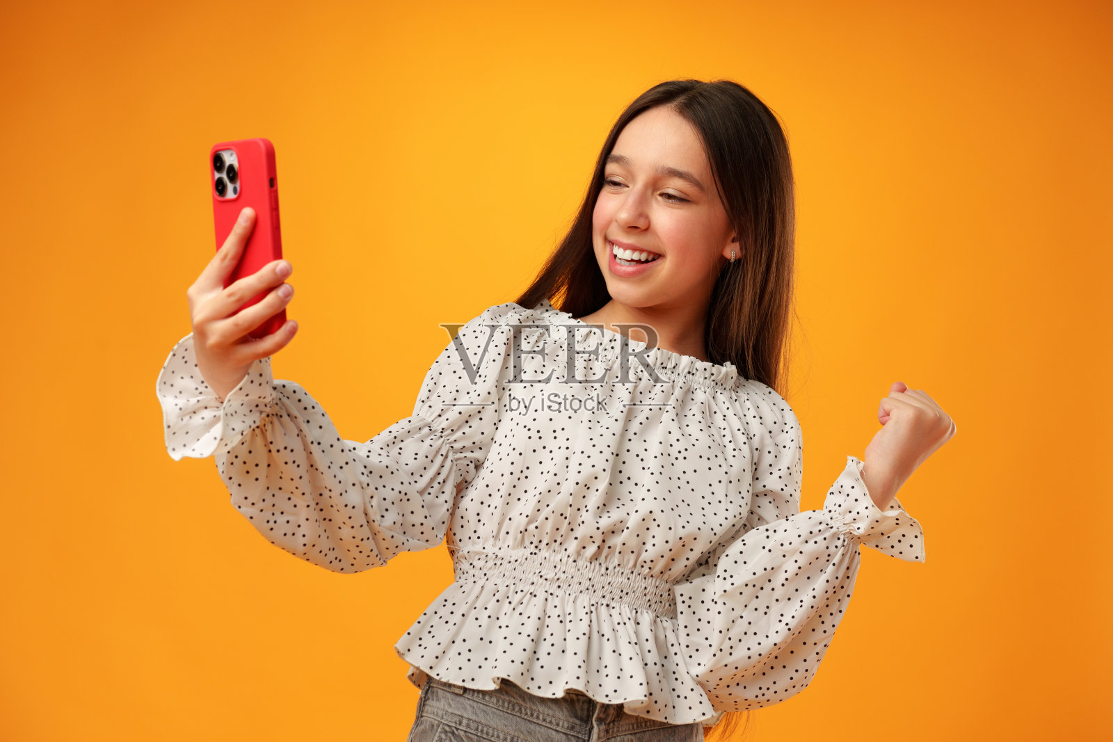 惊讶的少女在黄色背景下使用手机照片摄影图片