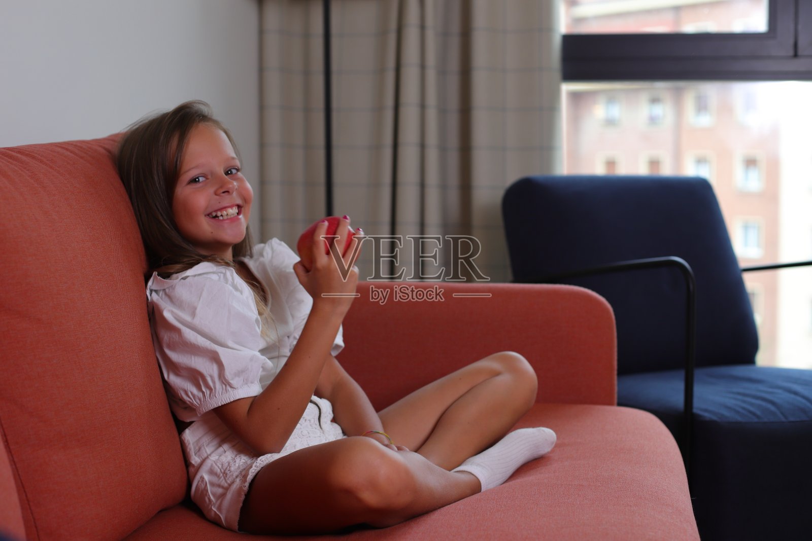 小女孩坐在沙发上吃苹果，生活方式矫健，饮食健康照片摄影图片