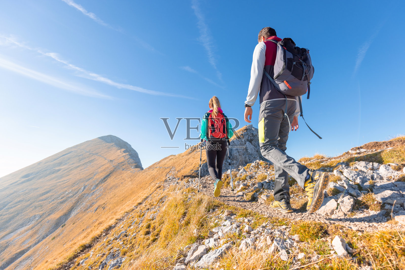 登山夫妇背着背包和登山杖在山上徒步旅行照片摄影图片