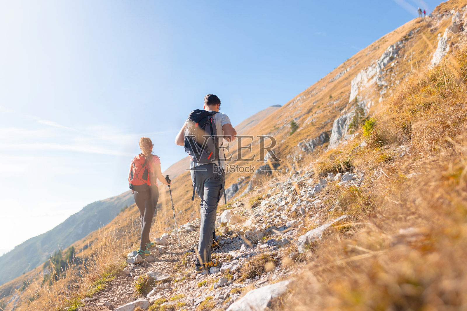 在一个阳光明媚的日子里，女人和男人在山间徒步旅行照片摄影图片