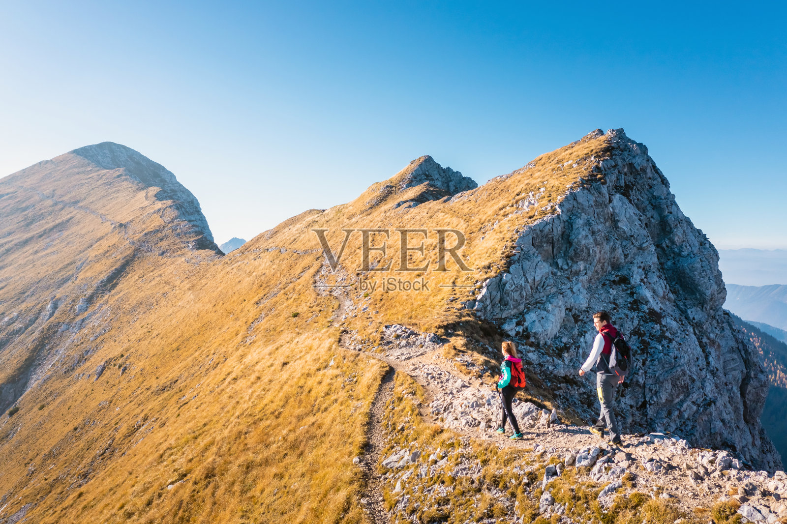 一对夫妇徒步旅行，走上坡，欣赏山脉的景色照片摄影图片