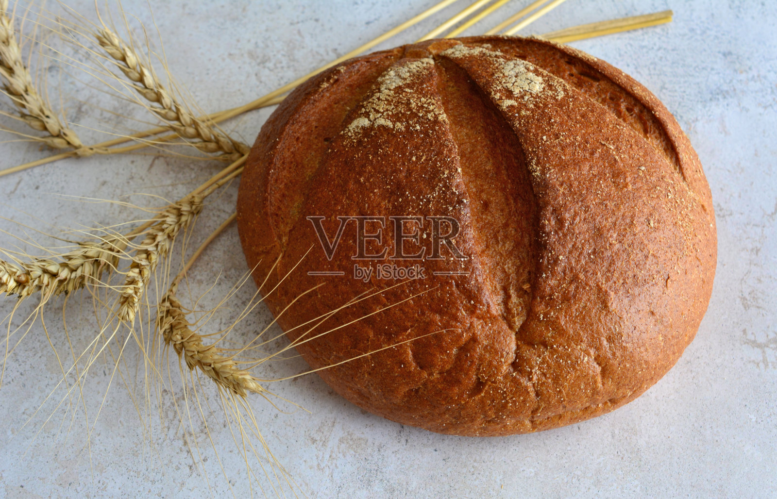 圆形的烤面包孤立在灰色的背景上，用小麦装饰照片摄影图片