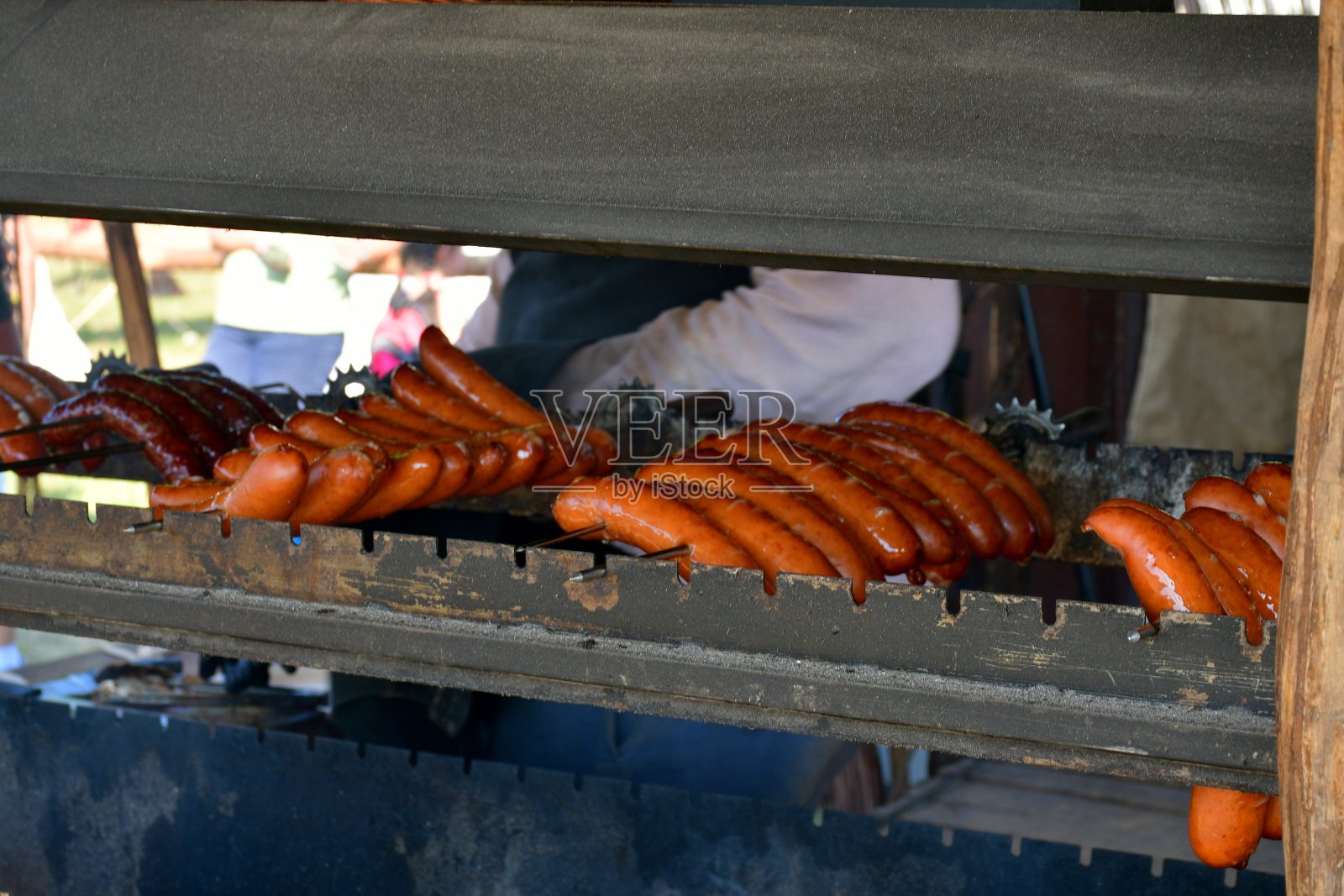 在波兰一个阳光明媚的夏日，一组各种各样的香肠和波兰熏肠在一个由金属制成的临时烤架上烤和煎，下面有一个小篝火照片摄影图片