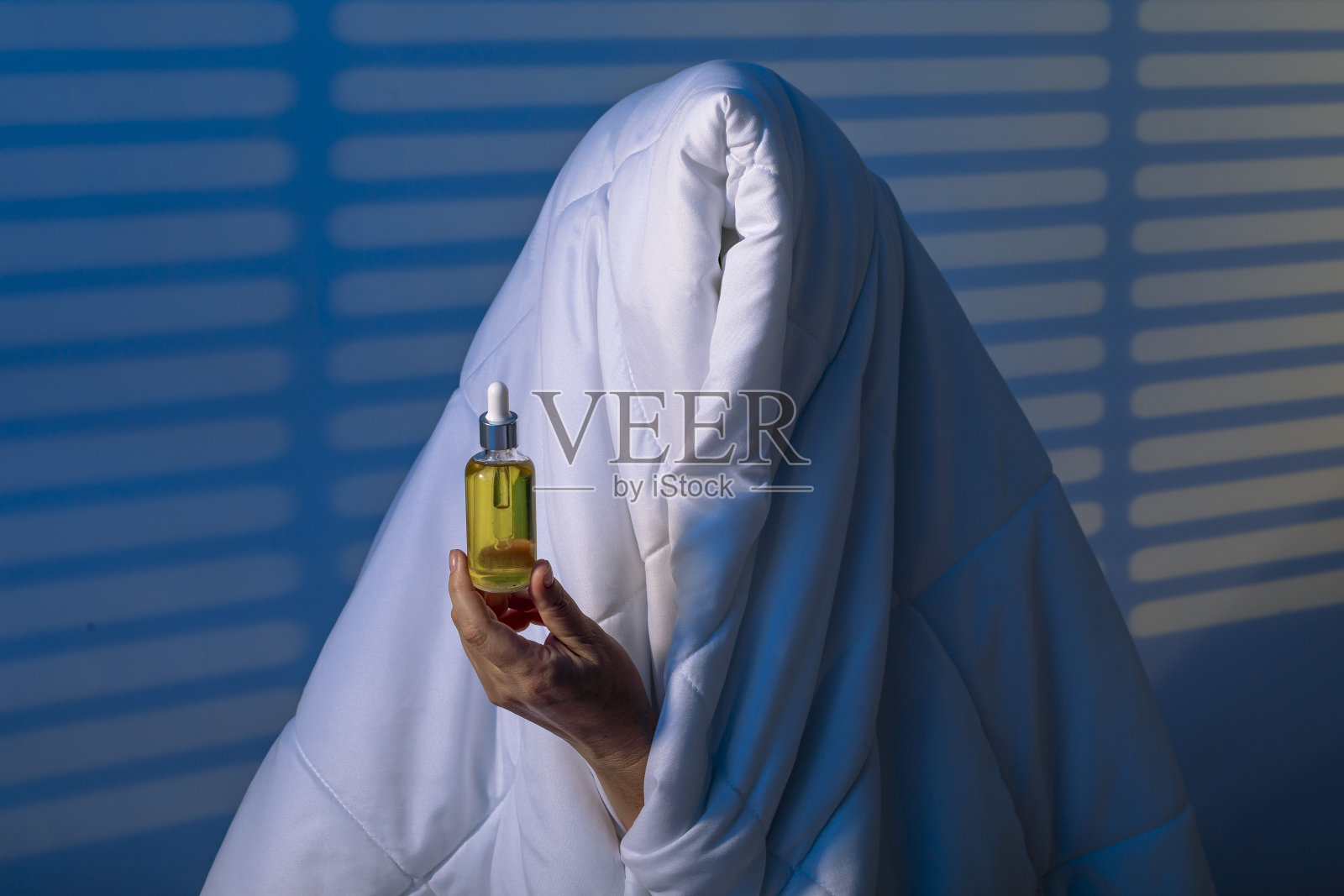 寻找宁静:女孩在他信任的毯子下用睡眠油与失眠作斗争。照片摄影图片