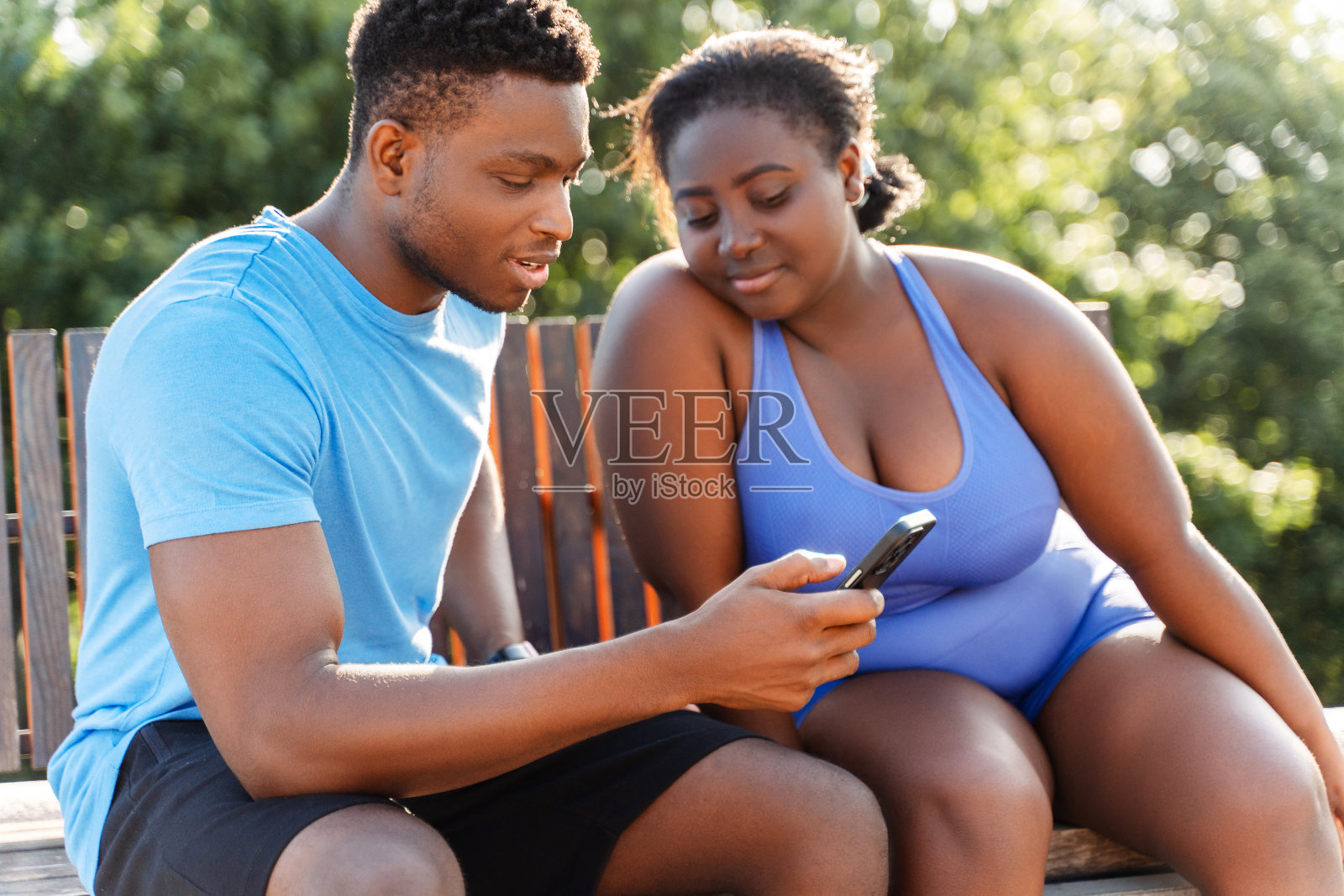 一名非洲男子手持手机，与一名非洲女子一起观看视频照片摄影图片