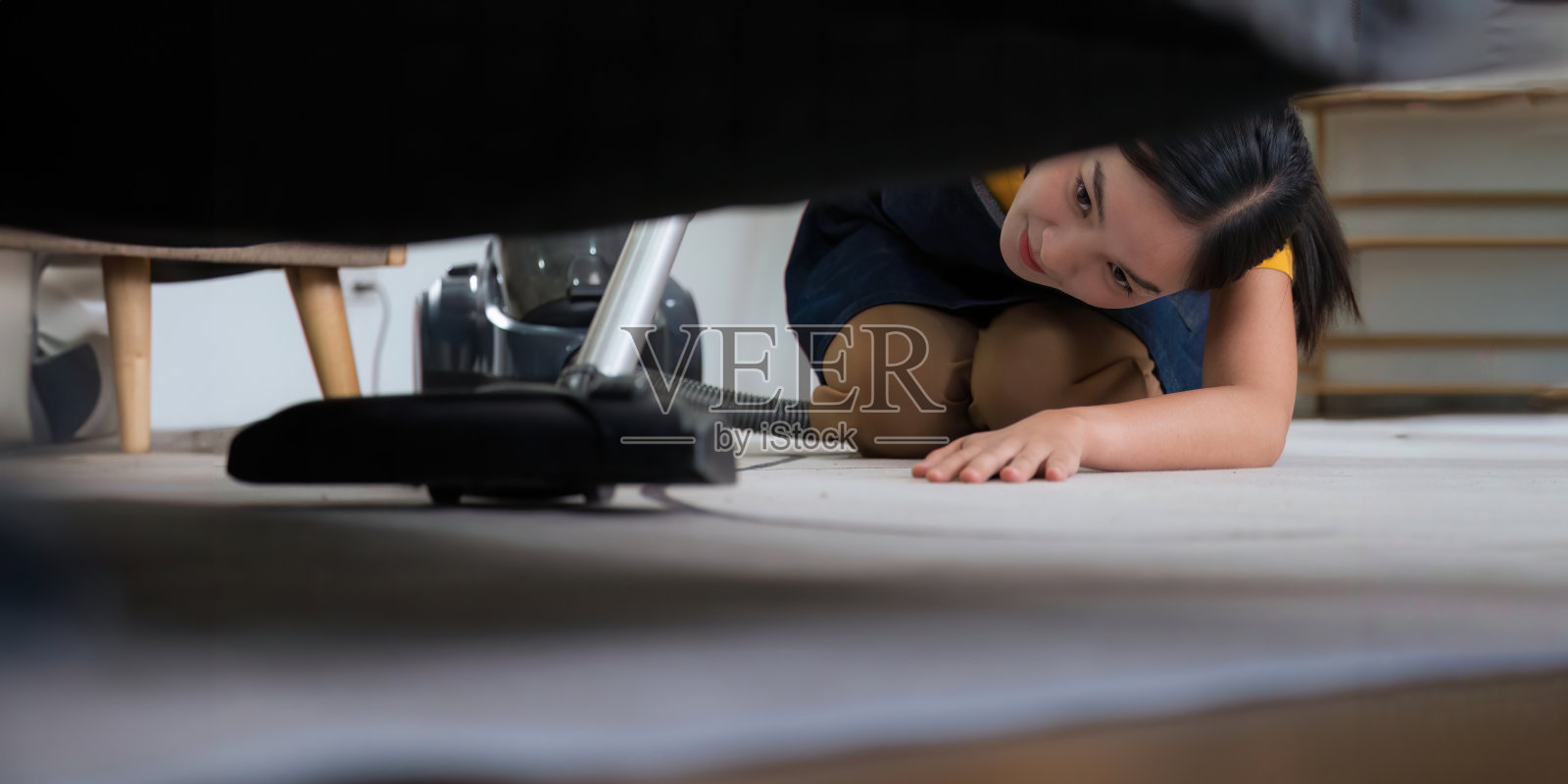 年轻的亚洲妇女在家里使用吸尘器。带吸尘器的公寓地板。照片摄影图片