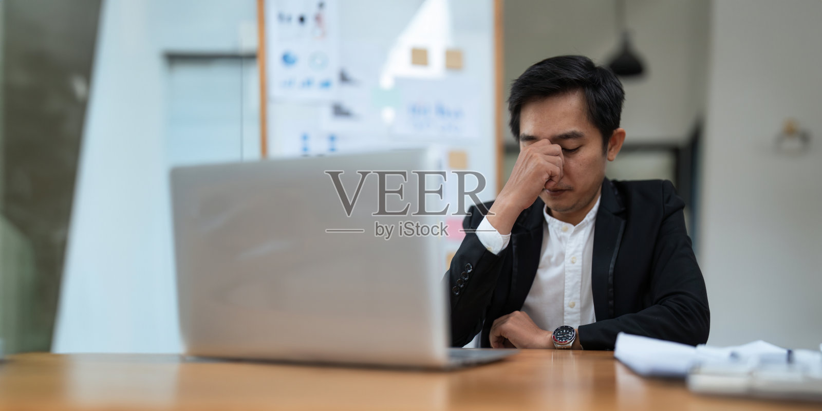 亚洲商人在电脑前工作时感到压力，在办公室头痛，工作时感到恶心照片摄影图片