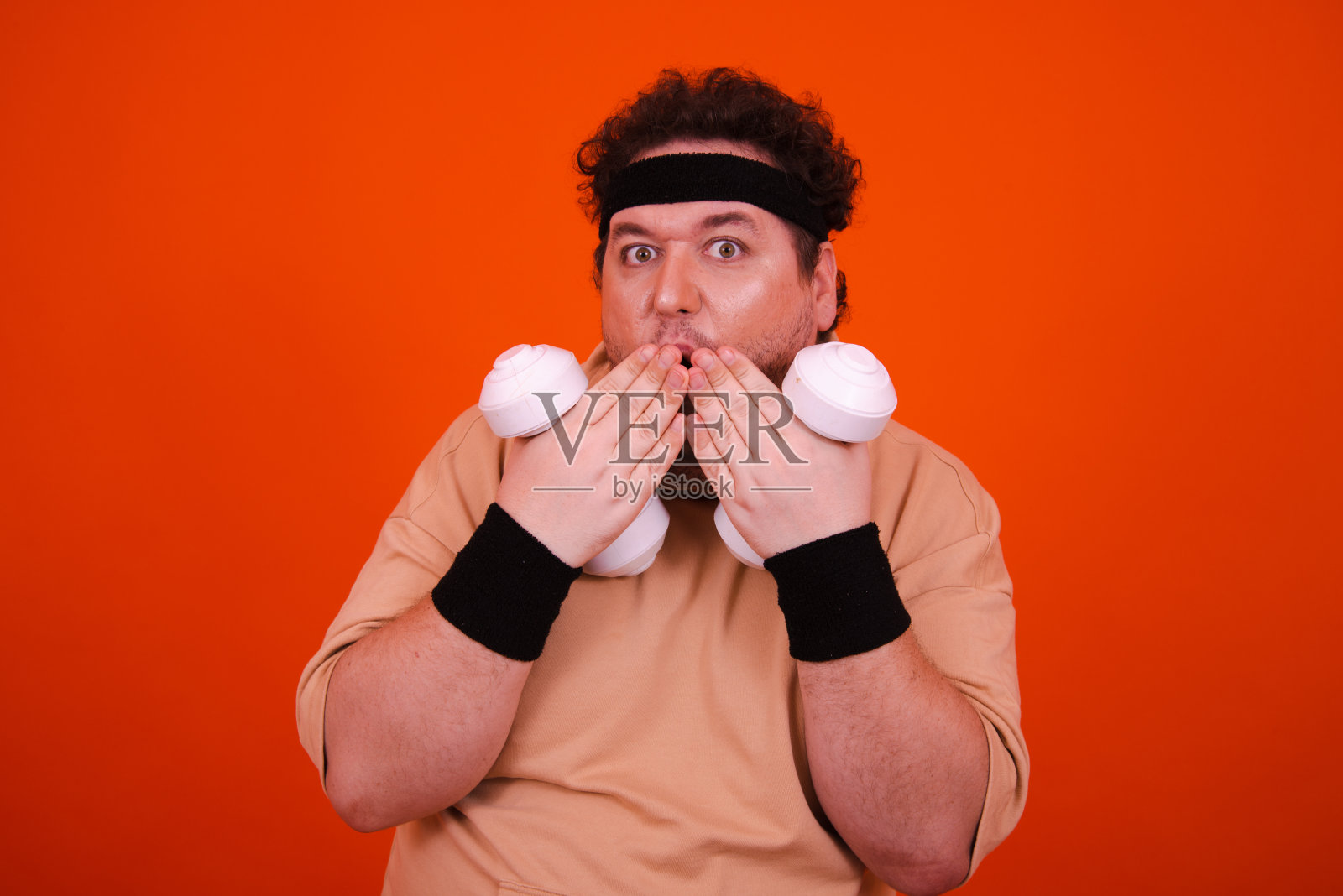 在健身房里健身吃甜甜圈的滑稽胖子。照片摄影图片