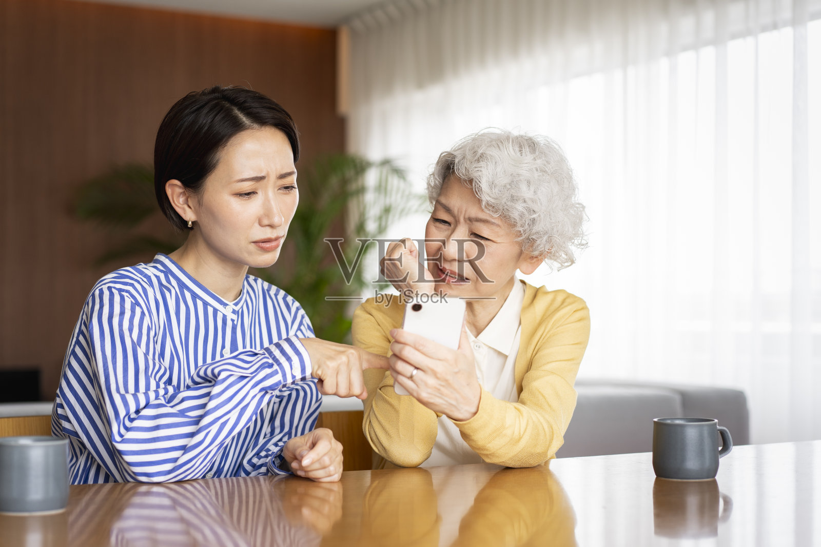 两个亚洲女人在一起看手机。照片摄影图片