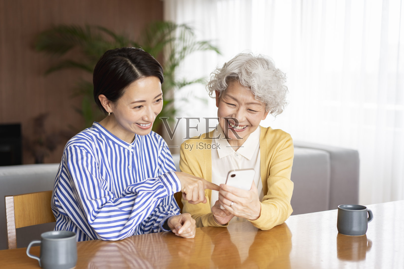 两个亚洲女人在一起看手机。照片摄影图片