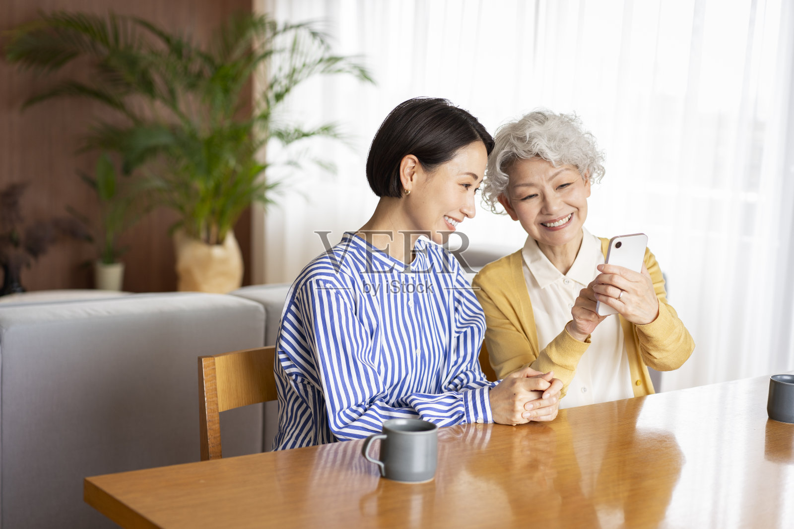 两个亚洲女人在一起看手机。照片摄影图片