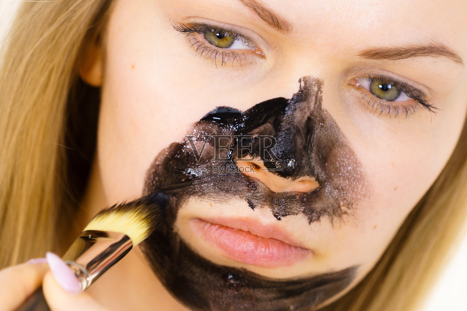 女孩正把黑色面膜敷在皮肤上照片摄影图片