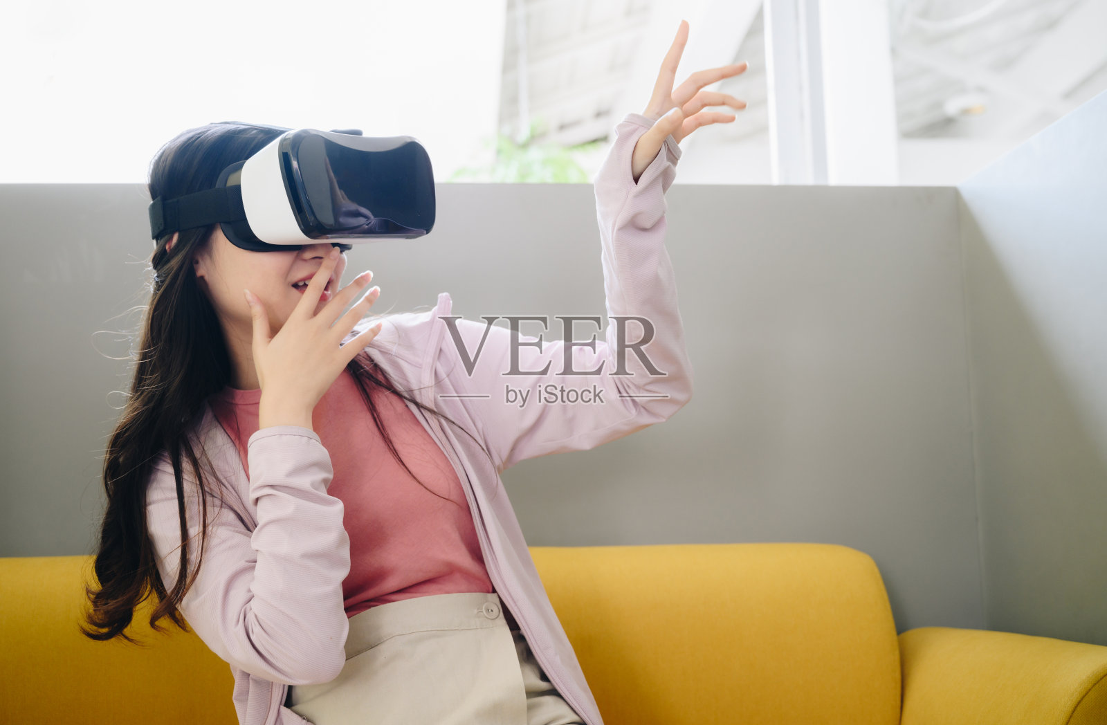 年轻的亚洲女性戴着虚拟现实眼镜，享受着视觉现实的体验。照片摄影图片