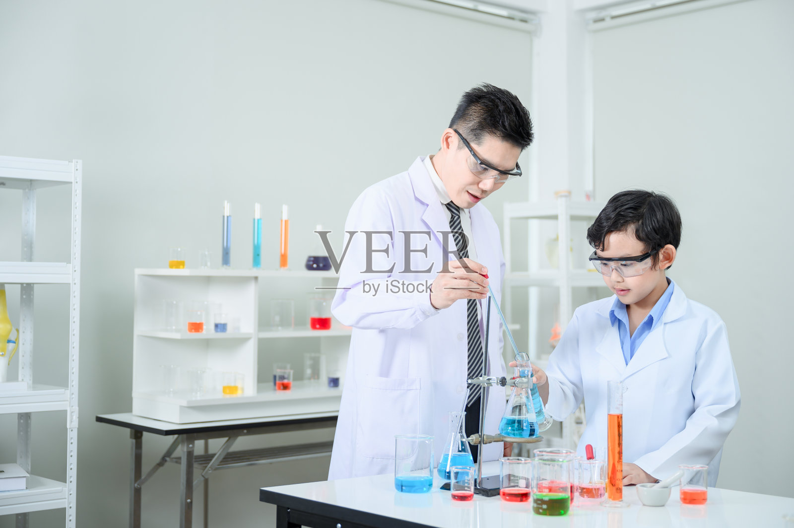 老师正在学习和研究实验室教那个男孩。照片摄影图片