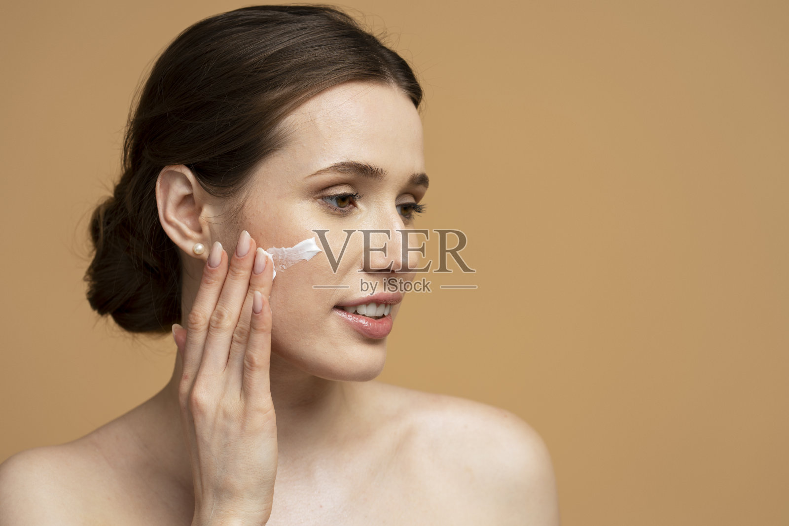 美丽微笑的年轻女子的特写肖像，脸上涂着面霜，看着别处照片摄影图片