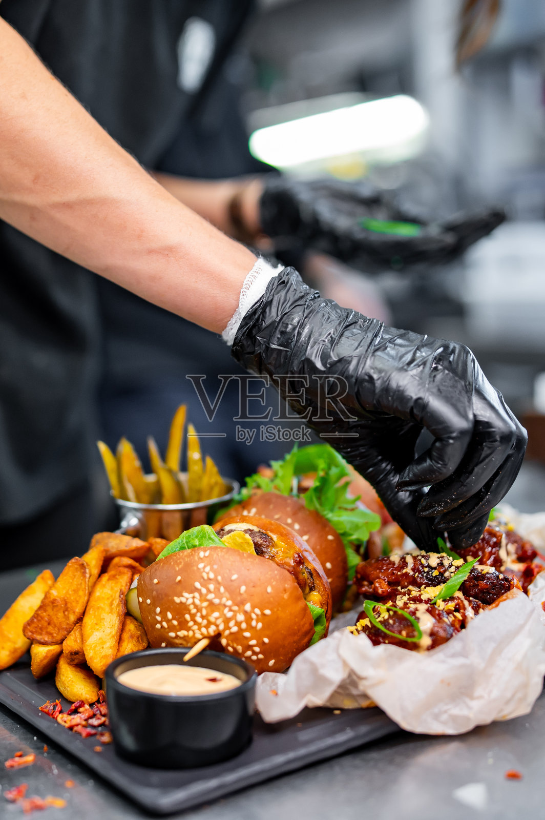 厨师正在烹调装在盘子里的快餐。汉堡，鸡翅在厨房照片摄影图片
