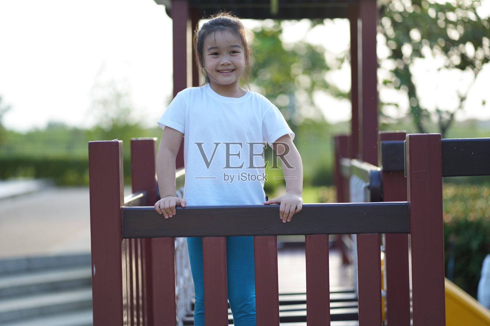 小亚洲女孩在操场上快乐地玩耍，对着镜头微笑照片摄影图片