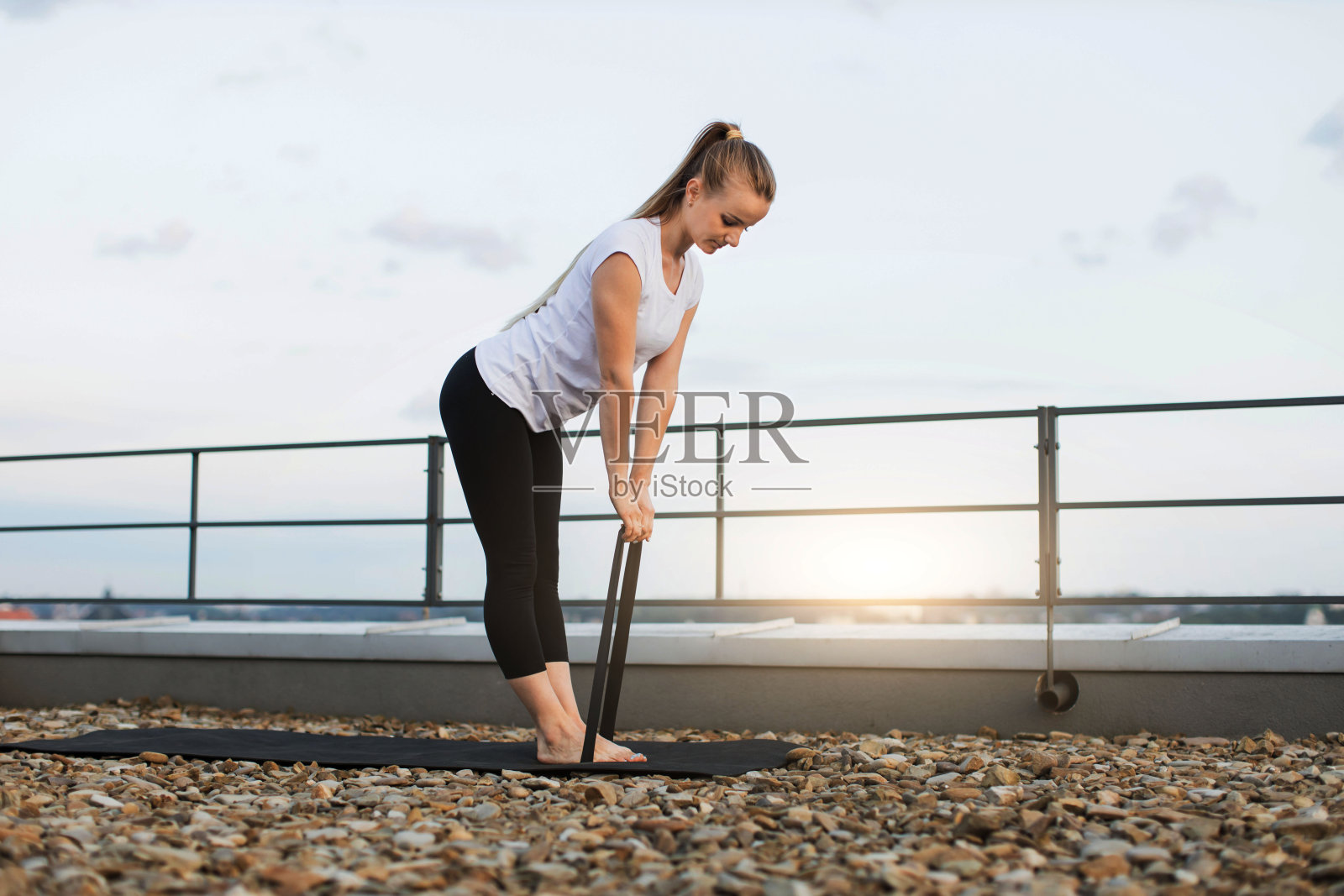 女性在户外的垫子上锻炼伸展带照片摄影图片