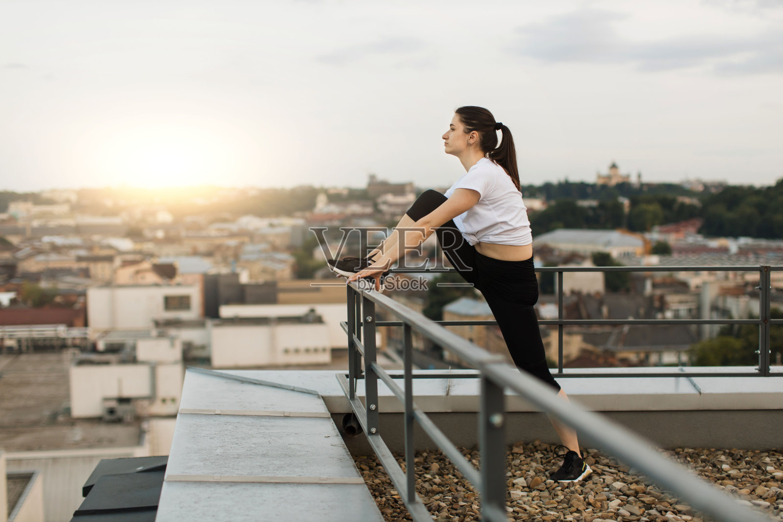 女子在屋顶训练后把腿放在扶手上照片摄影图片