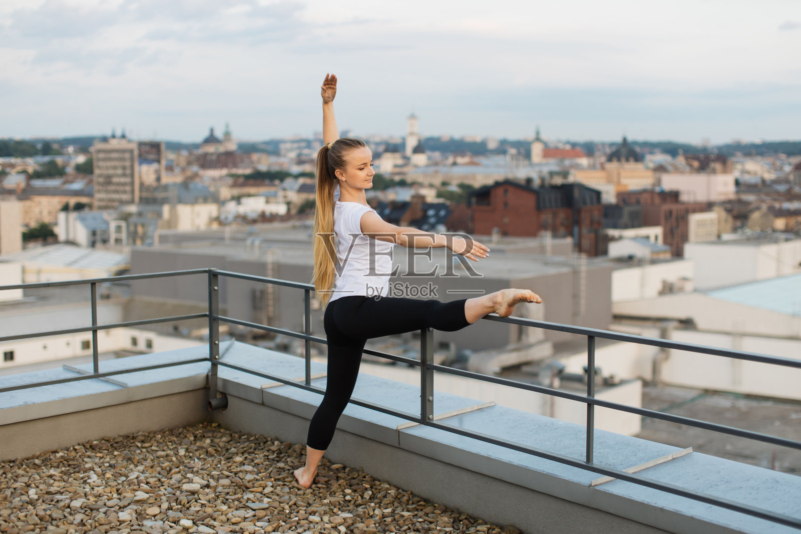 日落时分，人们在屋顶扶手上伸展腿部肌肉照片摄影图片