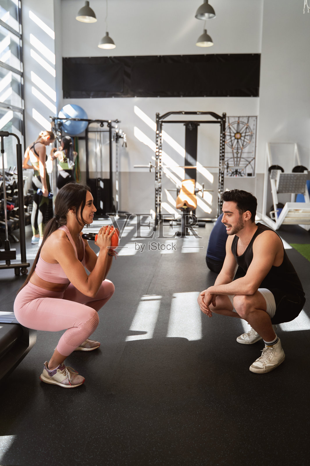 女运动员在健身房与私人教练一起锻炼时使用壶铃。照片摄影图片