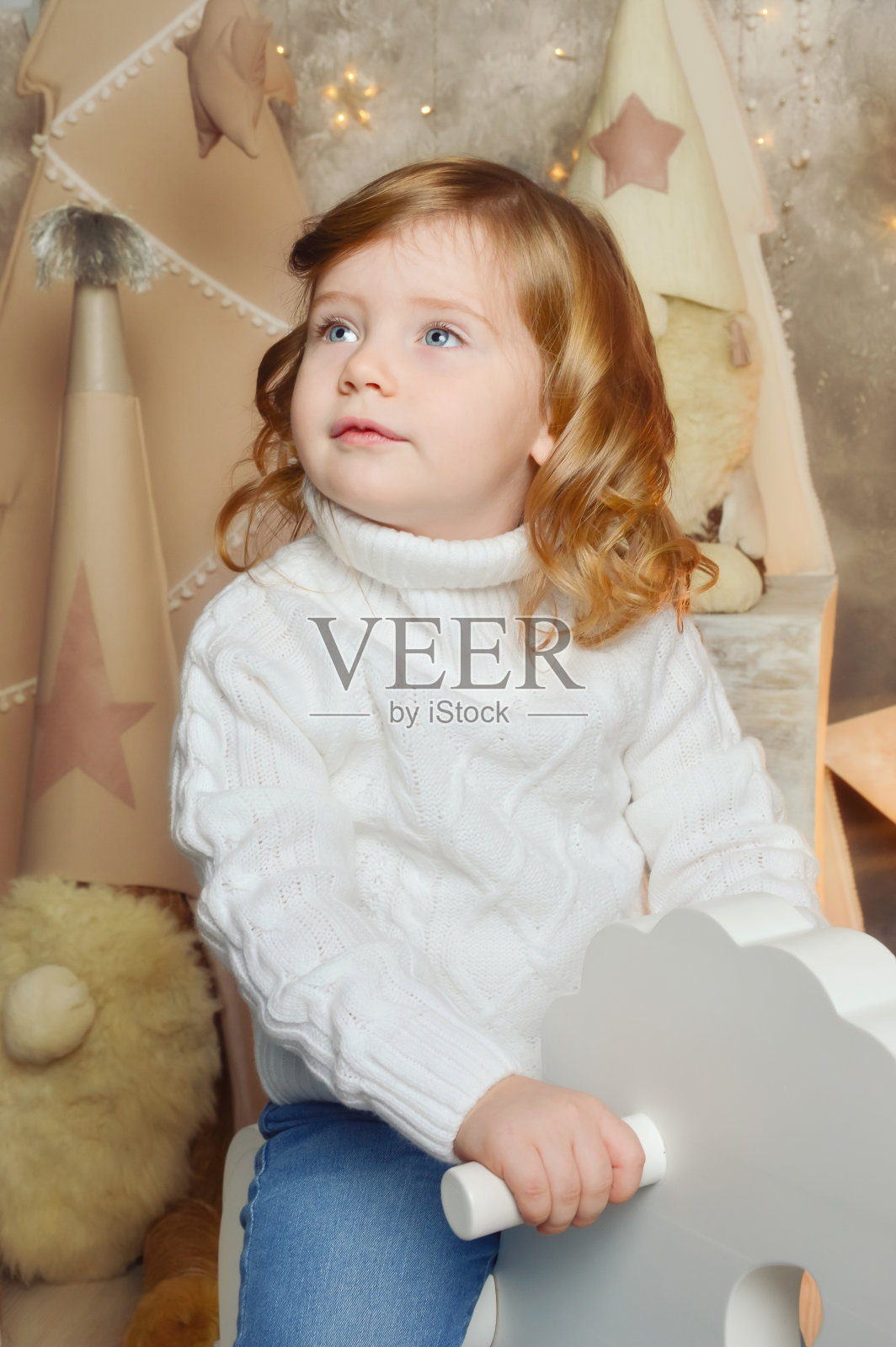 一个穿着白色针织毛衣的卷发女孩。新年快乐，圣诞快乐。寒假照片摄影图片