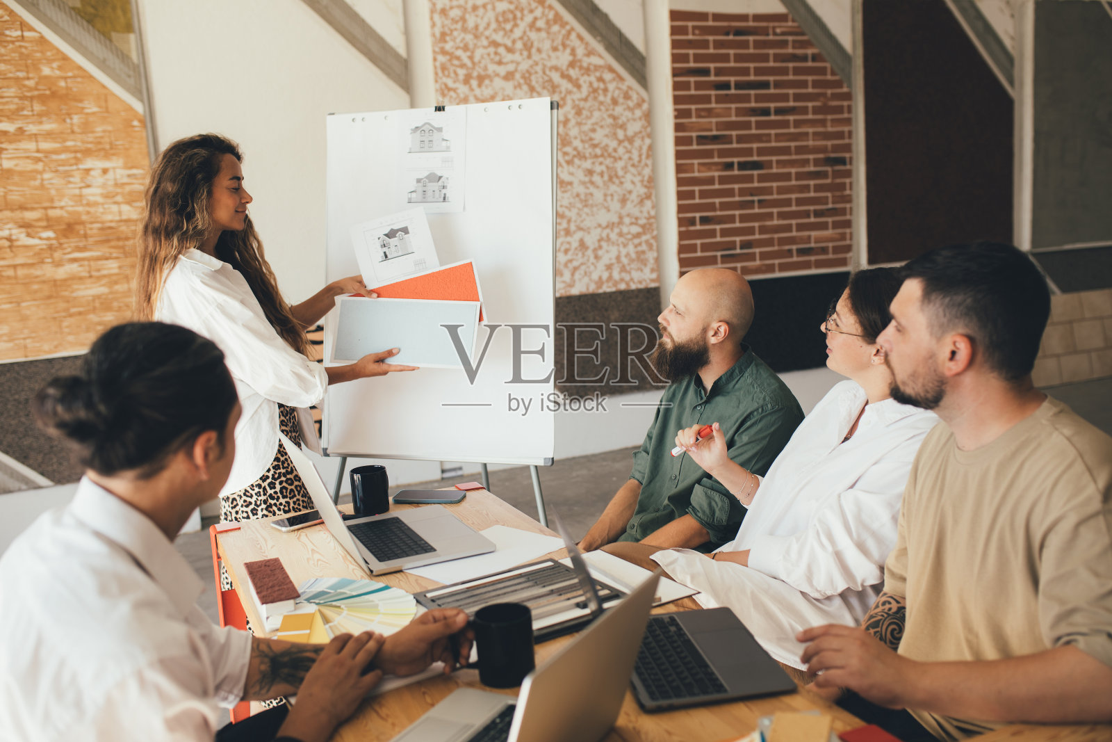 一群年轻的设计师在一间现代化的办公室里开会。照片摄影图片