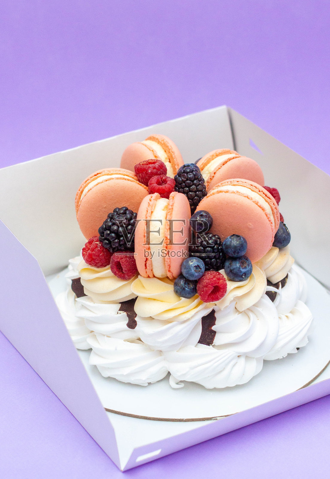 美味的甜点，有搅打的蛋清，奶油芝士漩涡，巧克力酱，新鲜浆果和紫色背景的马卡龙照片摄影图片
