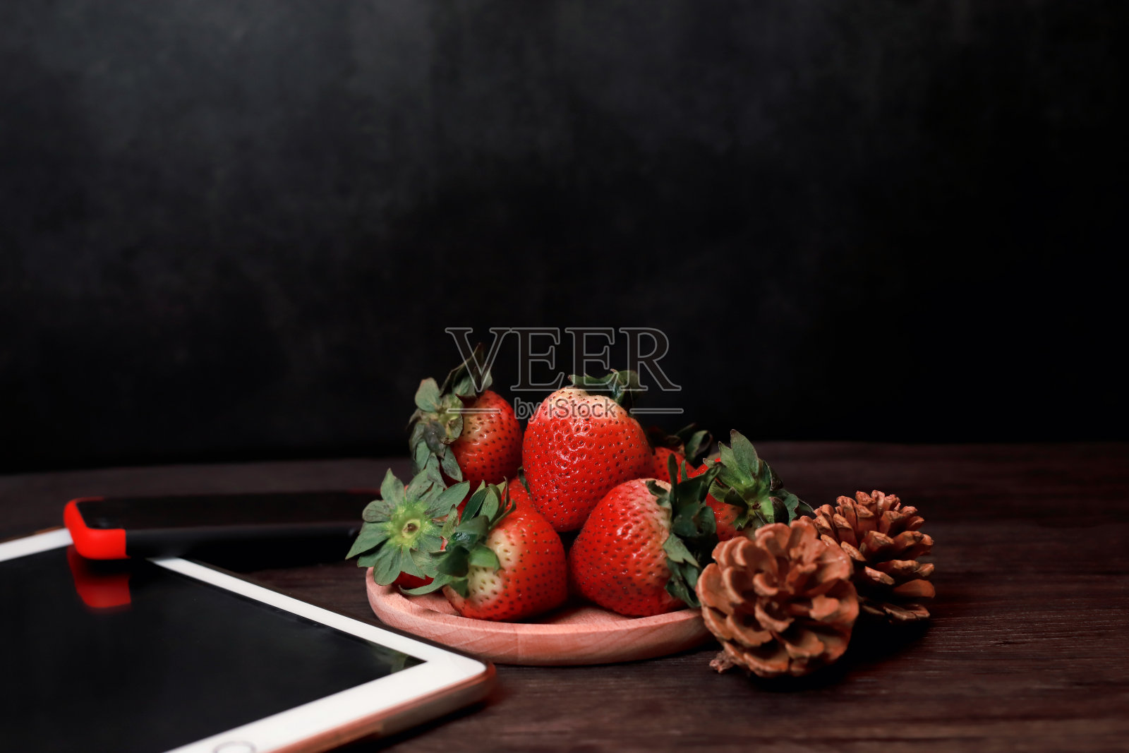 黑色背景的木托盘上放着草莓照片摄影图片