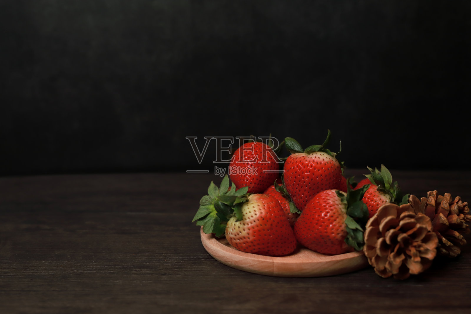 黑色背景的木托盘上放着草莓照片摄影图片