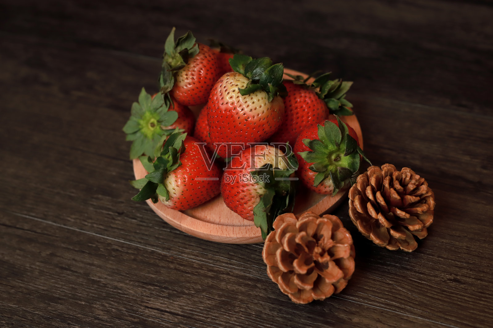 黑色背景的木托盘上放着草莓照片摄影图片