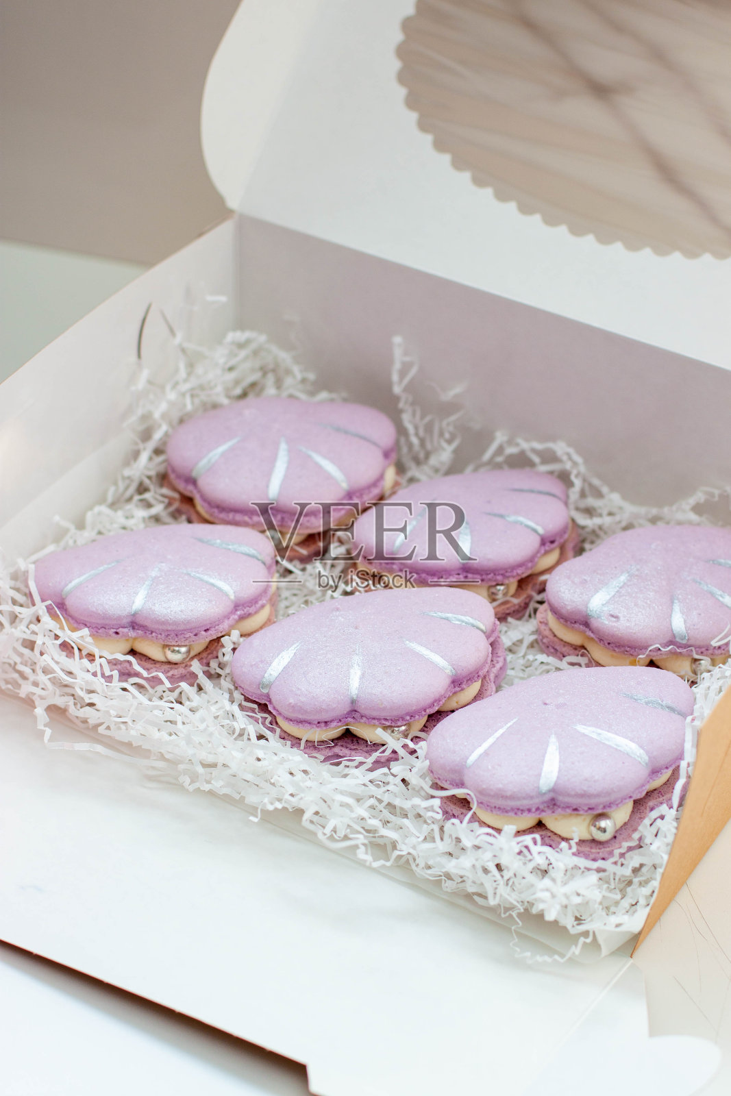 礼盒里的贝壳形状的法国马卡龙，颜色是柔和柔和的紫色照片摄影图片